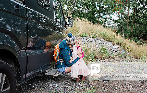 mother and daughter hugging outside a camper van whilst camping