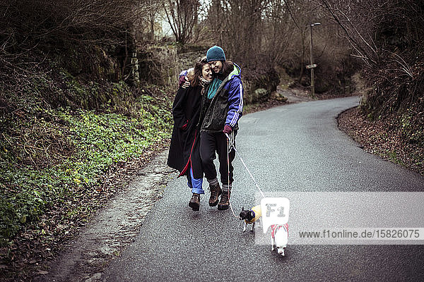 Schwules weibliches Paar lacht und geht im tschechischen Winter mit Hunden auf der Landstraße spazieren