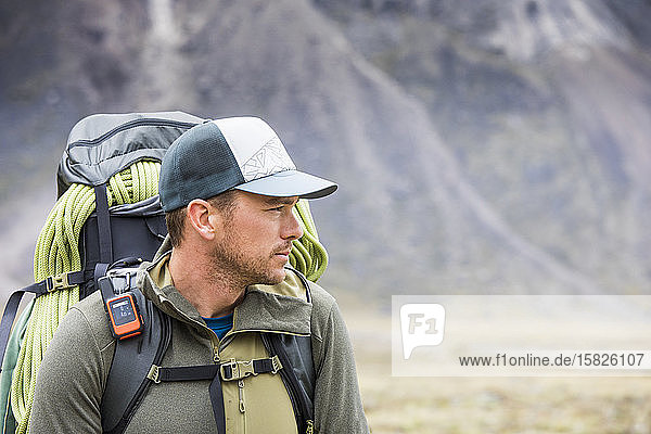 Portrait of determined backpacker carrying rope and navigation devie