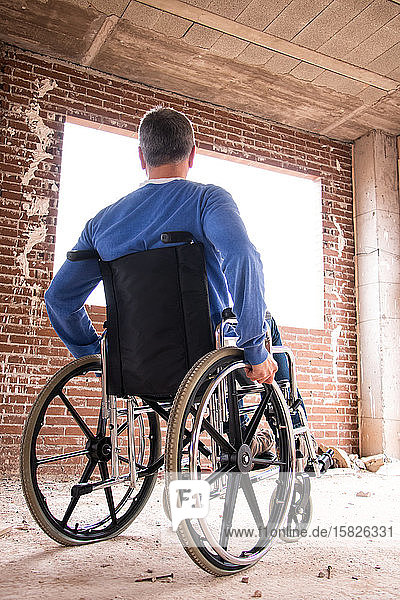 Ein Mann im Rollstuhl in einem im Bau befindlichen Haus mit Blick nach draußen