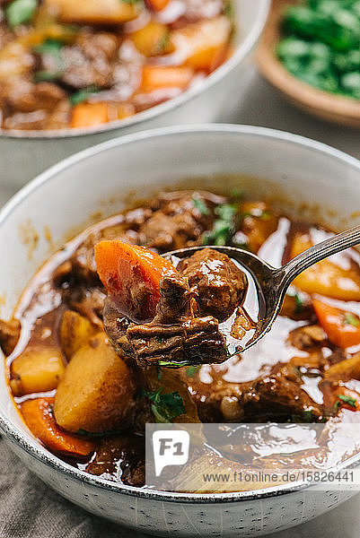 Beef stew presented on a spoon