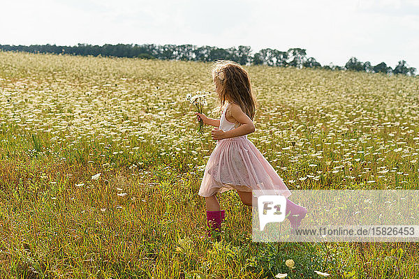 Kleines Mädchen  das im Sommer in einem Blumenfeld rennt.