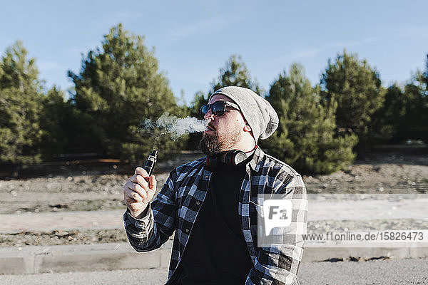 Junger Mann raucht mit einer elektronischen Zigarette