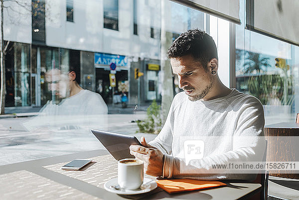Junger Mann benutzt Tablet-Computer im Café