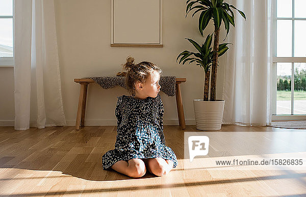 Porträt eines jungen Mädchens  das allein zu Hause sitzt und aus dem Fenster schaut
