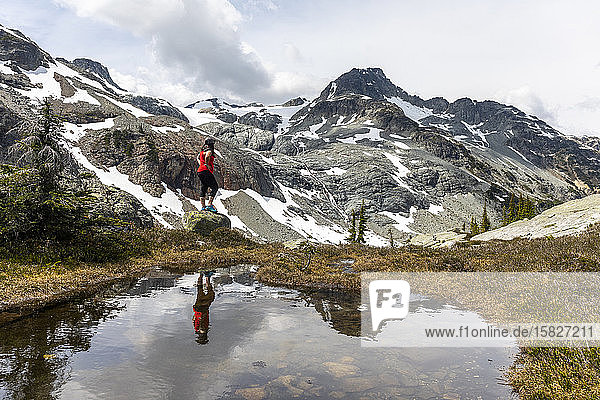 A women stands on a rock and celebrates Canada on a summer day in the mountains of British Columbia.