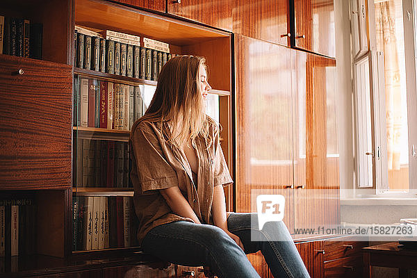 Junge Frau am Bücherregal sitzend