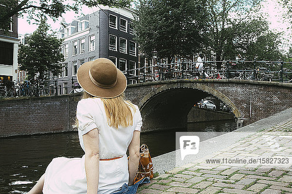 Frau sitzt am Kanal mit Blick auf die Stadt