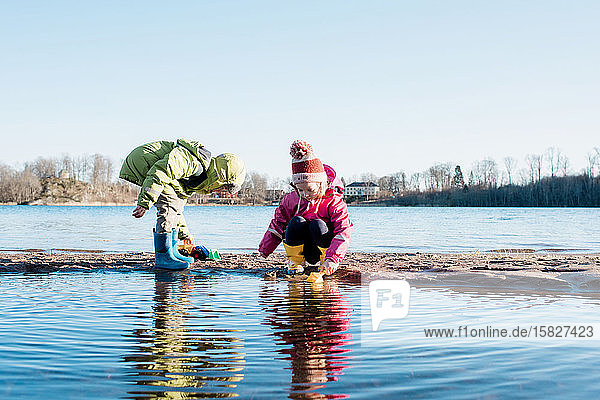 Geschwister spielen im Winter in Schweden gemeinsam am sonnigen Strand