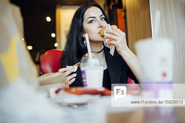Frau isst einen Hamburger in einem Cafe