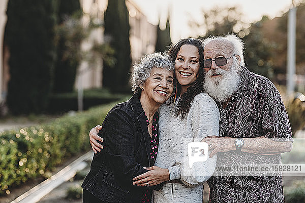 Porträt eines aktiven älteren Ehepaares und einer erwachsenen Tochter lächelnd
