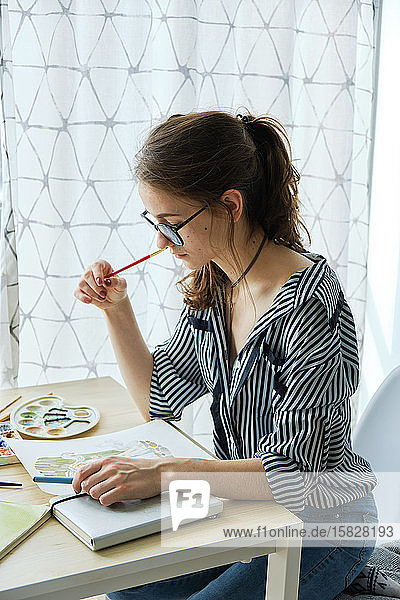 tausendjähriges Mädchen malt fabelhafte Bilder auf Papier  während sie zu Hause sitzt