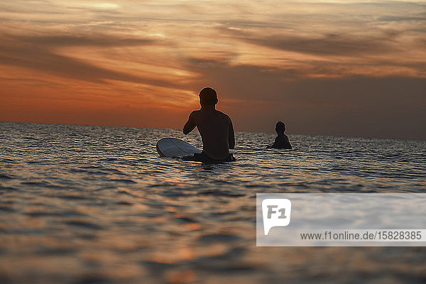 Two surfers in ocean at sunset