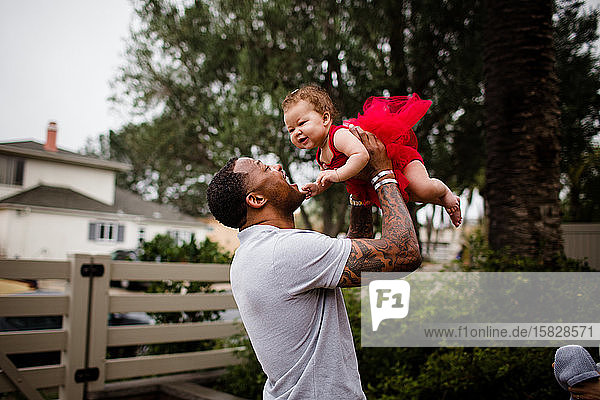 African American Dad Holding Biracial Daughter and Smiling