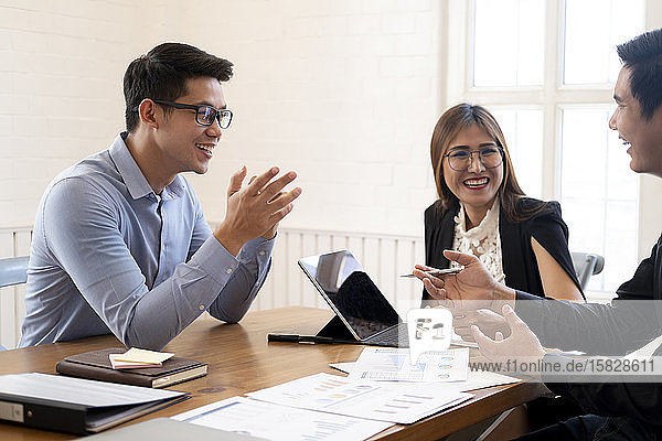 Geschäftsleute lachen zusammen  während sie über Papierkram diskutieren