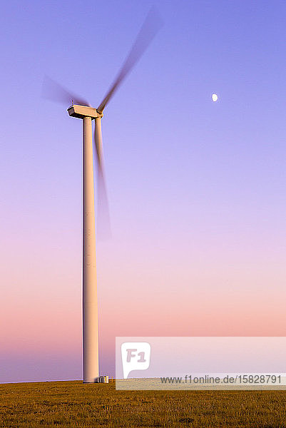 Windturbine in Bewegung gegen violetten Himmel mit Mond