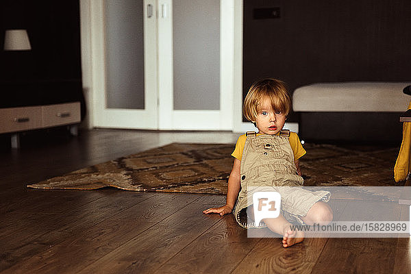 Kleiner Junge sitzt auf dem Teppich im Haus
