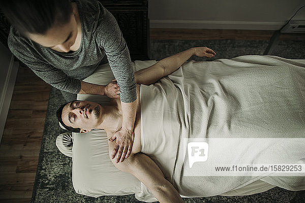 Weibliche Massagetherapeutin übt Druck auf die Schultern des Mannes aus