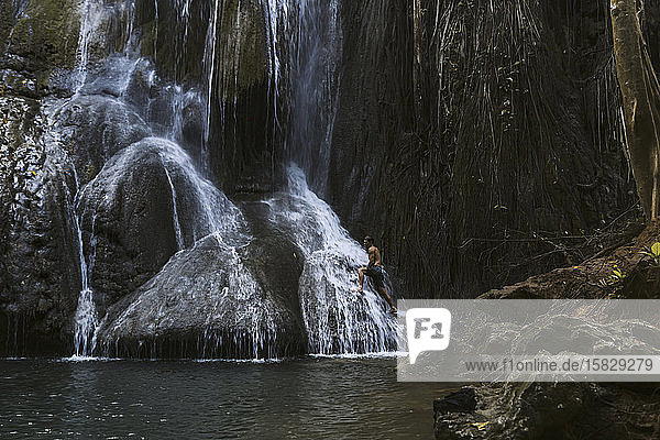 Junger Mann geht am Wasserfall spazieren