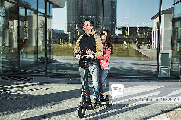loving young millennials having fun walking on an electric scooter