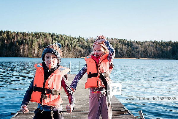 brother and sister playing at the beach wearing life jackets in winter