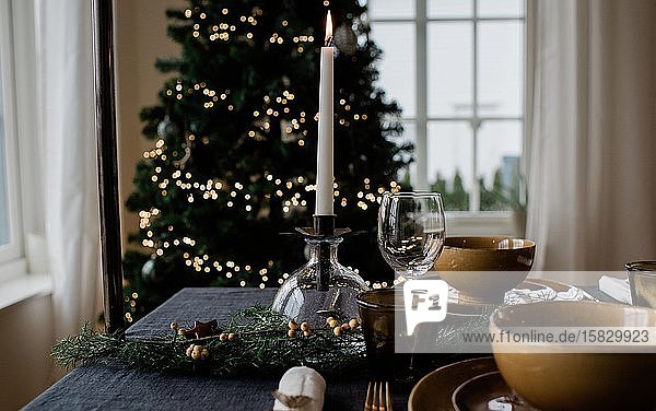 angezündete Kerze auf einer festlich gedeckten Tafel zu Weihnachten