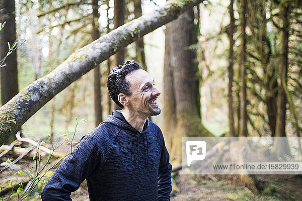 Portrait of man wearing sweater smiling in the forest.