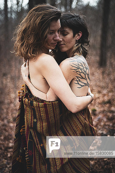 natürliche Schönheit Homosexuelles weibliches Paar umarmt sich unter einem Schal in winterlichen Wäldern