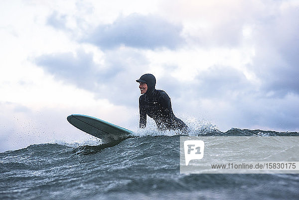 Frau genießt an einem windigen Tag das Surfen im Winter