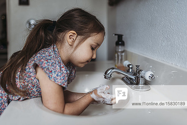 Seitenansicht eines jungen Mädchens  das sich im Waschbecken mit Seife die Hände wäscht