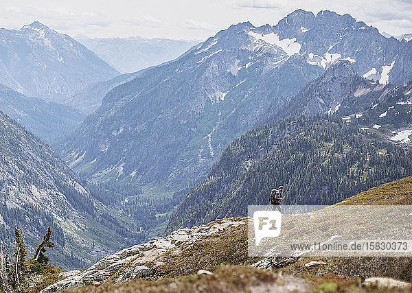 A male hiker walks on a trail with a view in the Cascades  Washington