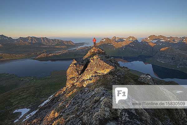 Male hiker overlooks mountain landscape of Selfjord area from summit of Kitind  MoskenesÃ¸y  Lofoten Islands  Norway