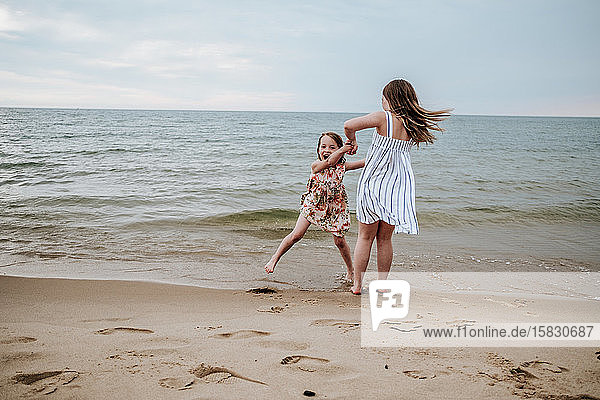 Schwestern tanzen und spielen am Strand des Lake Michigan