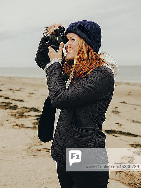Woman taking photos on beach in Scotland