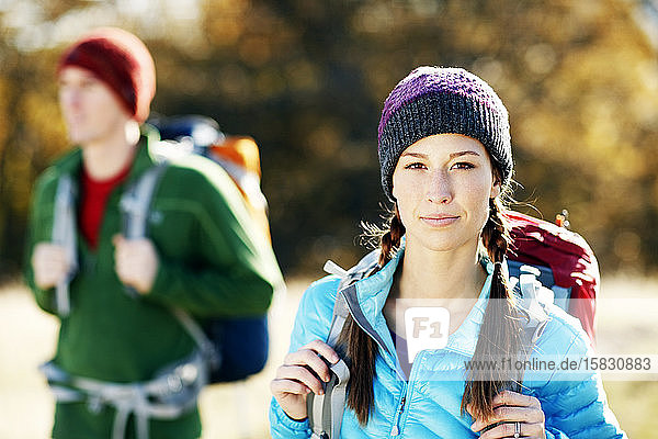 Female backpacker looking at camera with male backpacker in background