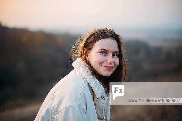 Porträt einer schönen jungen Frau in warmer Kleidung bei Sonnenuntergang