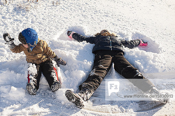 Brother and Sister playing in the snow in front yard
