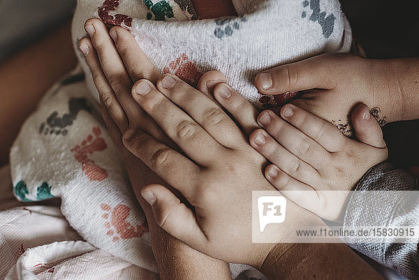 Detailaufnahme der Hände der ganzen Familie  die den neugeborenen Sohn im Krankenhaus halten