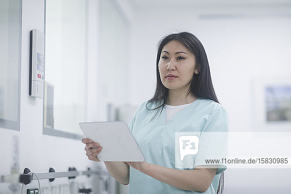 asiatische Krankenschwester mit Tablette in einem Krankenhaus