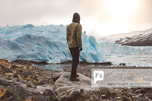 Unbekannter Mann auf Felsblock in Gletschernähe stehend