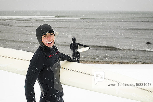 Women getting ready to surf on a snowy day