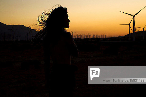 Silhouette einer Frau vor dem Windpark bei Sonnenuntergang