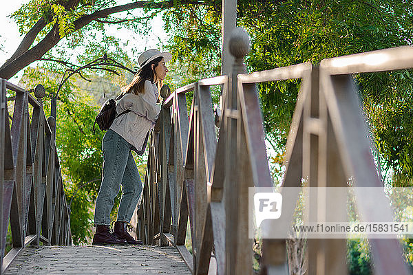 Junge Frau mit Hut steht auf einer Parkbrücke. Abenteuer  Tourismus.