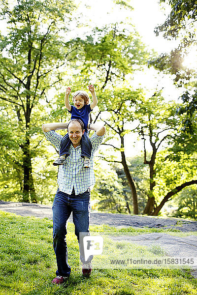 Dad holding son on shoulders in park