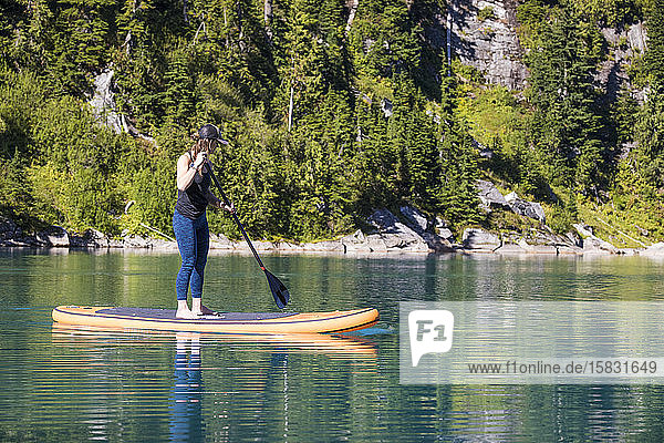 Junge Frau paddelt auf einem abgelegenen See an Bord.