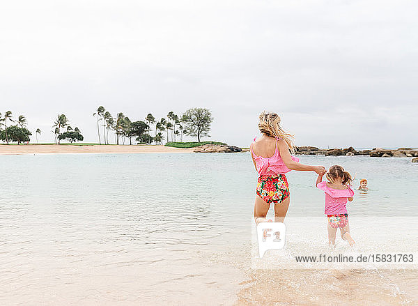 Mutter und Tochter spielen im Ozean