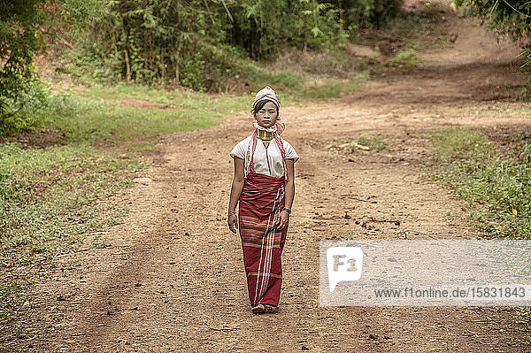 Langhalsfrau geht auf dem Feldweg des Stammes
