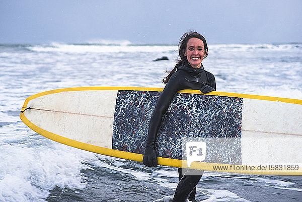 Frau genießt an einem windigen Tag das Surfen im Winter