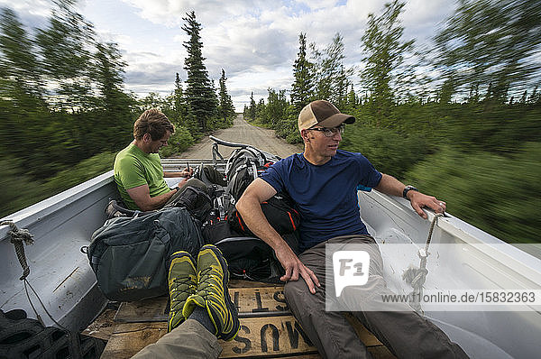 Drei Männer trampen auf der Ladefläche eines Pick-ups in Alaska