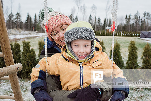 Mutter und Sohn lachen und haben Spass beim Spielen draussen im Schnee